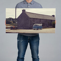 A man holds a 80x40cm panoramic canvas print featuring a photo of a camper van parked in Ballydehob. 