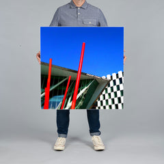 A person holds a square 80x80cm canvas print against a plain gray studio background. The canvas features a photograph of the Grand Canal Theatre in Dublin Docklands. 